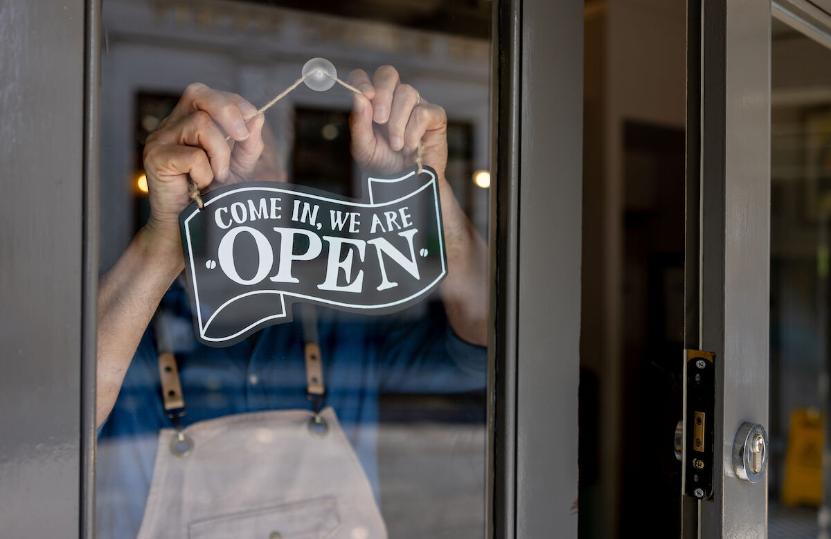 Small business owner with a business open sign